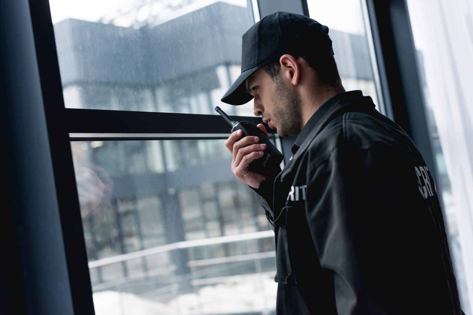 handsome guard in black uniform talking on walkie talkie