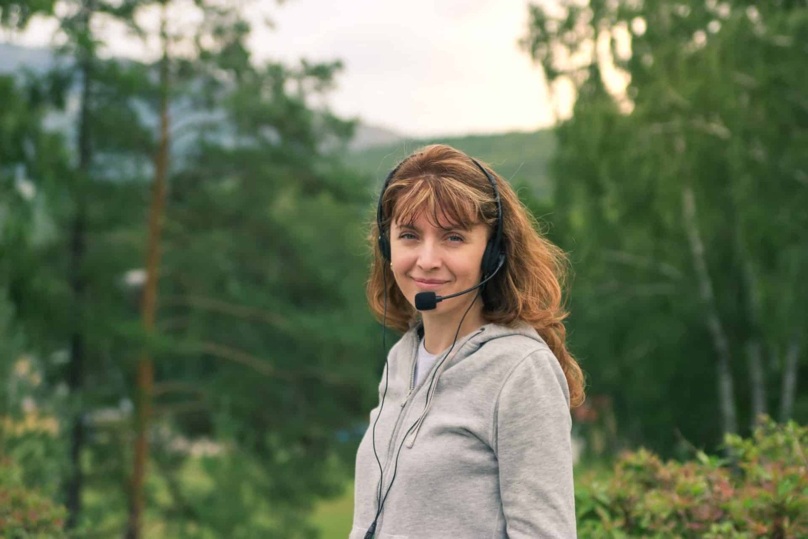 millennial smiling woman wearing headset mountains landscape p